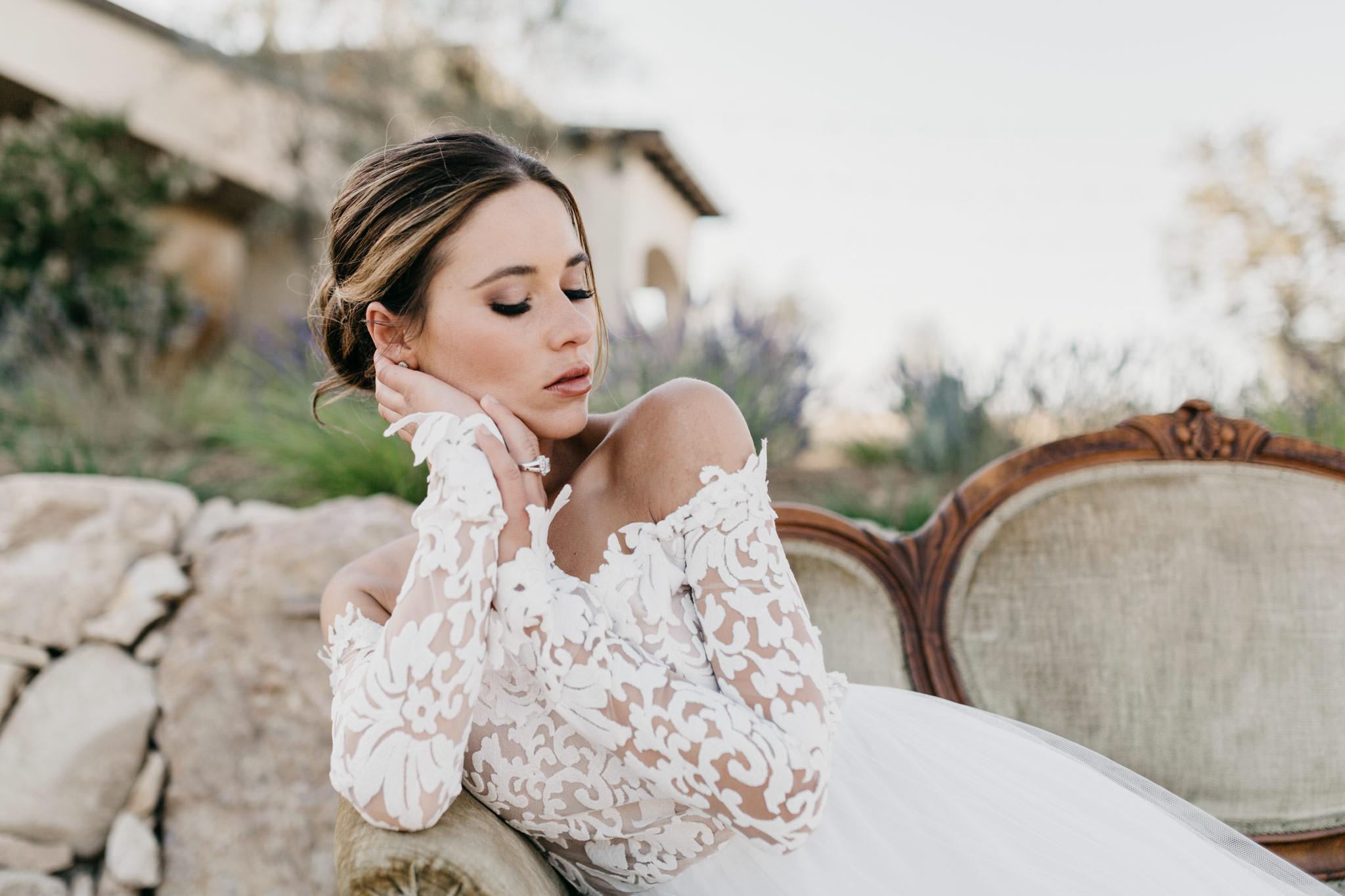 Bride sitting on vintage couch with her eyes closed showing off her makeup
